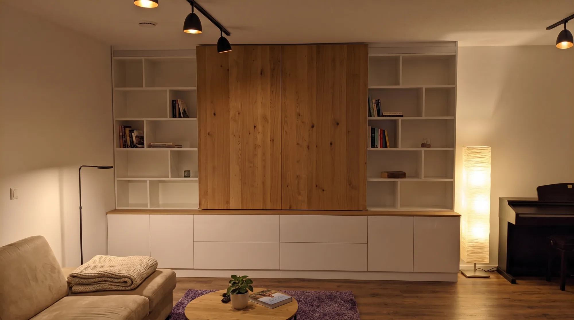 Wohnwand nach Maß am Abend mit warmer LED-Beleuchtung und geschlossenen Eiche-Elementen